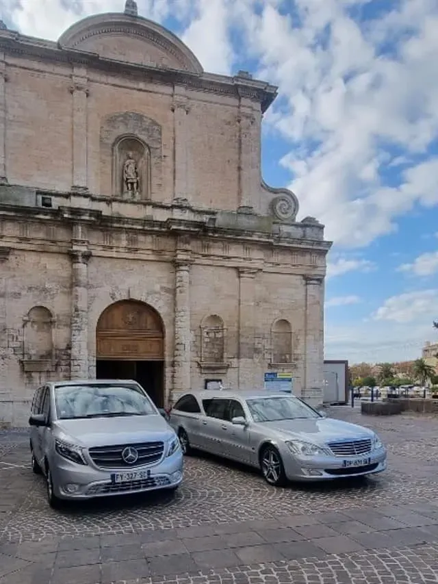 Corbillard et véhicule de convoi funéraire de marque Mercedes devant une église