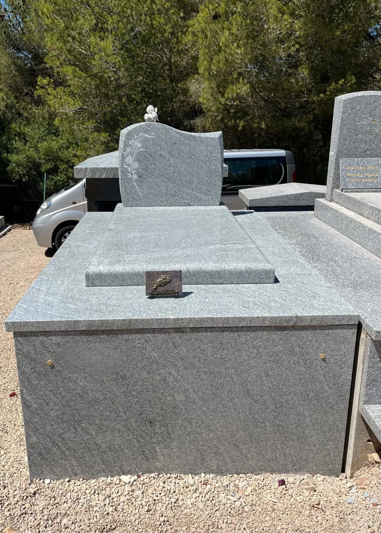 Monument funéraire massif en granit gris avec stèle ornée de motifs floraux gravés