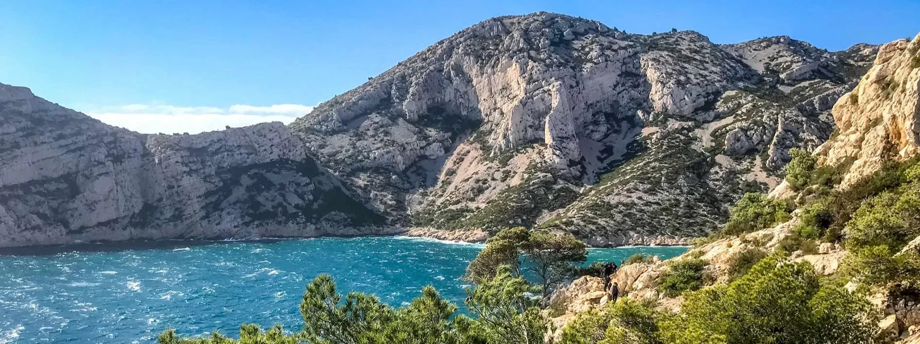 Vue panoramique d'une calanque méditerranéenne aux eaux turquoises bordée de falaises rocheuses