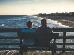 Couple sénior assit de dos sur un banc face à la mer profitant d'une retraite sereine