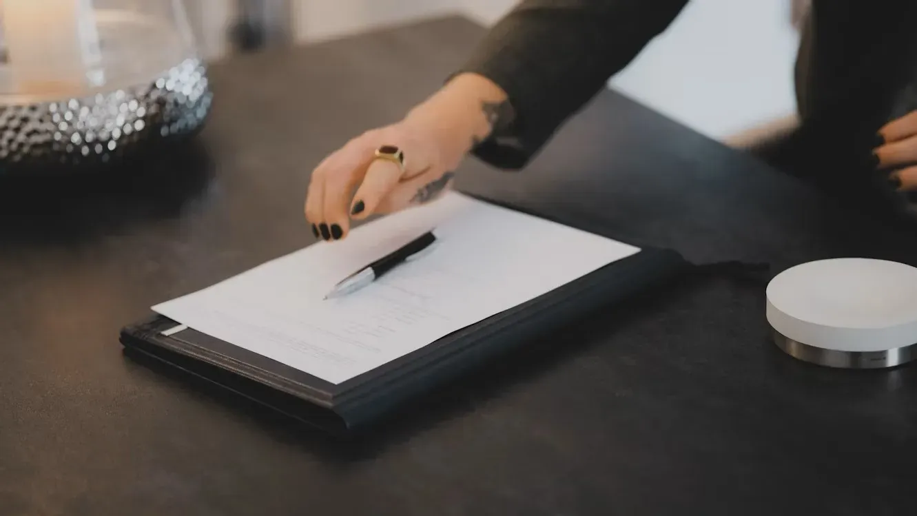 Main posant un stylo sur un document officiel pour la souscription d'un contrat obsèques